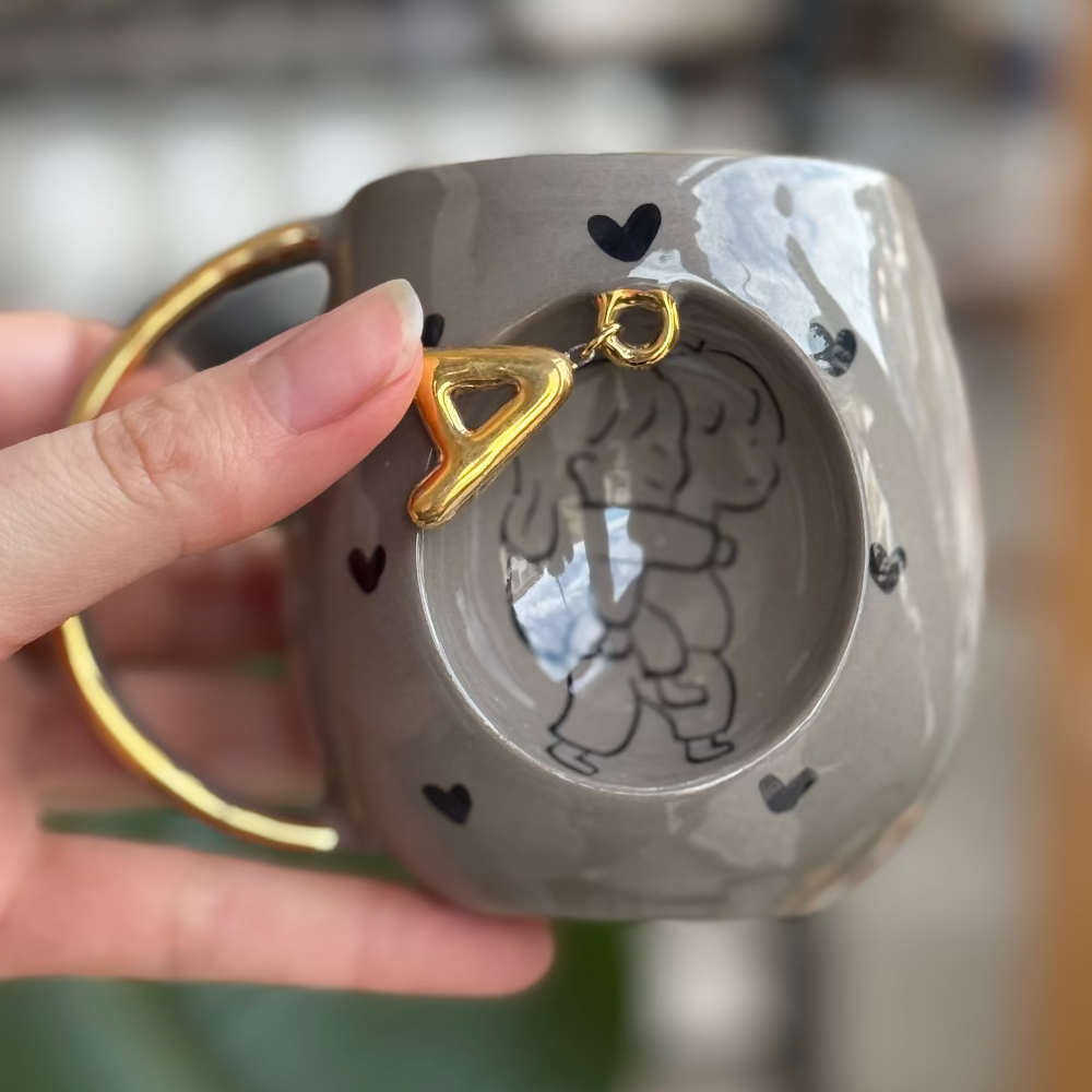 sevgilisini taşıyan çocuk taupe rengi kupa A harfi takılı resmin açık hali